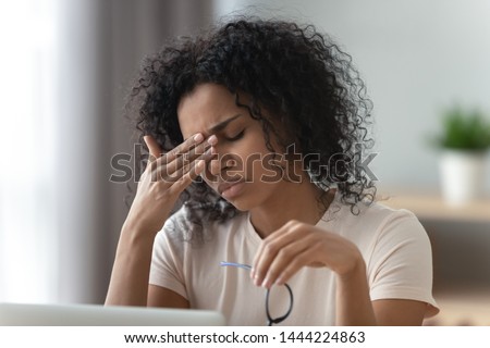 Tired stressed overworked young african woman student feel hurt fatigue eye strain headache after computer work take off glasses suffer from pain in dry eyes, bad vision problem, eyestrain concept Royalty-Free Stock Photo #1444224863