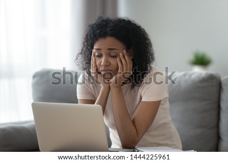 Bored young african american girl tired of learning sit at home looking at laptop, lazy apathetic black female university student frustrated about study computer work feeling uninterested demotivated Royalty-Free Stock Photo #1444225961
