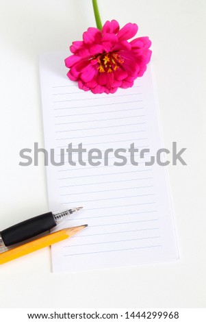 blank notepad with flower,pencil,pen on a white background top view