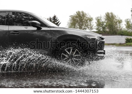 Modern car driving outdoors on rainy day