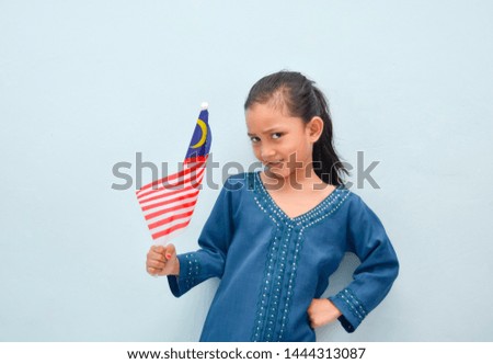 Malay girl holding Malaysia flag. Malaysia independence concept. Selective focus.