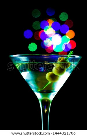 A martini glass with olives isolated on a black background