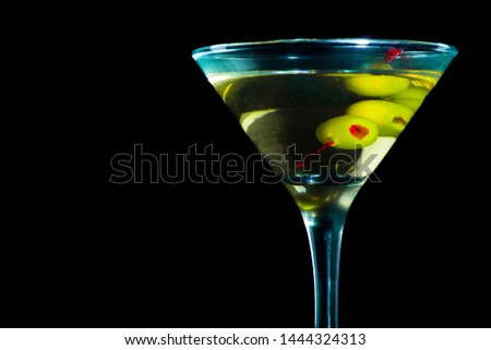 A martini glass with olives isolated on a black background
