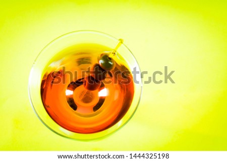 A martini glass with olives isolated on a yellow background