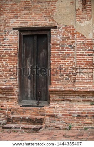 Red old and vintage style bricks and cement wall with an old wooden frame and door from a historic architecture in Ayutthaya Historical Park, Ayutthaya Province, Thailand, Asia.