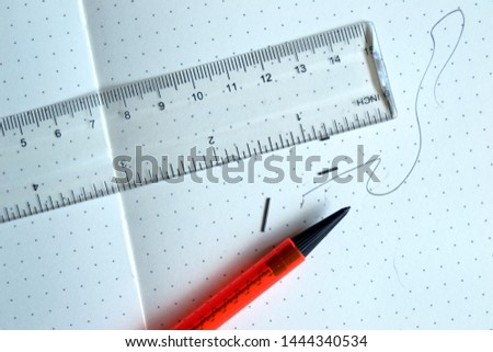Drawing pencil with plastic ruler on dot grid pad