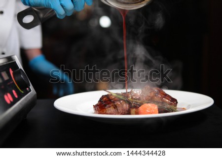 Cooks hands pour filemi sauce. Photo without a face. The concept of restaurant cooking meat dishes. Photos in the interior.