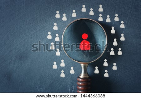 business image of magnifying glass with people icon over chalkboard background, building a strong team, human resources and management concept