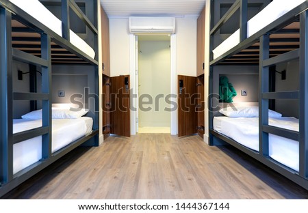 Hostel, hotel, dormitory beds on wooden floor with dim lighting. Accomodation for travelers. Clean and modern design. Bedroom with air condition.  Royalty-Free Stock Photo #1444367144