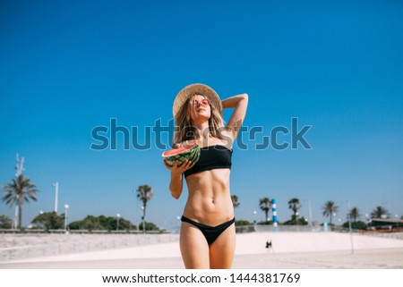 Tiny Beautiful girl having nice day at the beach with watrmelon and in fashion swimsuit