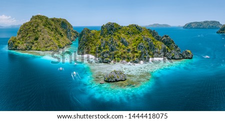 Aerial drone view of tropical Shimizu Island steep rocks and white sand beach in blue water El Nido, Palawan, Philippines. Tourist attraction most beautiful famous nature spot Marine Reserve Park Royalty-Free Stock Photo #1444418075