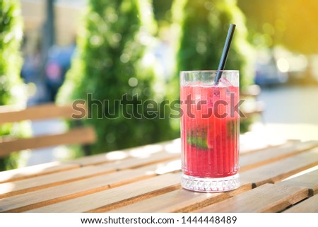 Cold summer refreshing cocktail on a wooden table in cafe outdoors