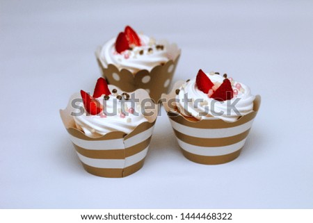 Close-up cupcakes with whipped eggs cream decorated fresh strawberry and chocolate balls on white background. Isolate