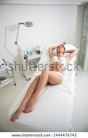 Healthy treatment. Top angle full length portrait of young graceful slender woman resting on massage couch in spa center in white underwear