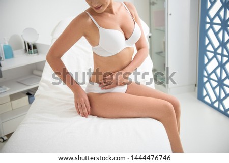 Healthy treatment. Top angle cropped head portrait of young graceful slender woman sitting on massage couch in spa center in white underwear