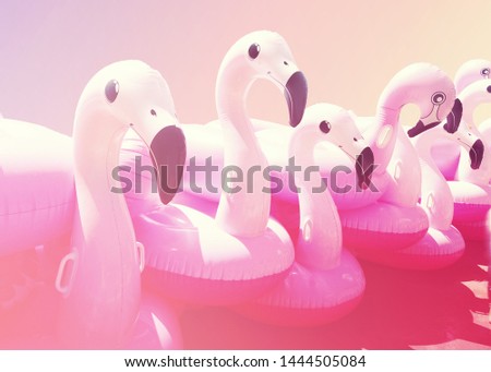 A lot of pink trendy blown beach flamingo on warm pastel gradient simple background. Summer party.