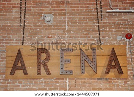 Arena metal sign posted in a  brick wall 