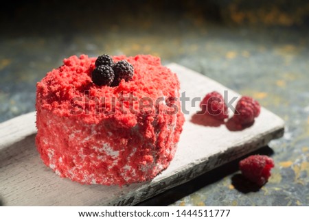 Red cake, on a wooden board, abstract background, decorated with raspberries. Confectionery. On a rustic background