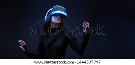 Beautiful woman with flowing hair over dark background. Girl in glasses of virtual reality. Augmented reality, science, future technology, robots and people concept. VR.