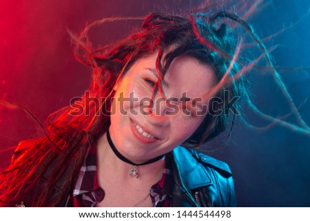 Youth, hairstyle and modern concept - young woman with dreadlocks smiling and having fun over the red and blue light background