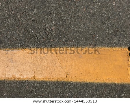 Yellow streak of old paint on gray asphalt road. Closeup photo