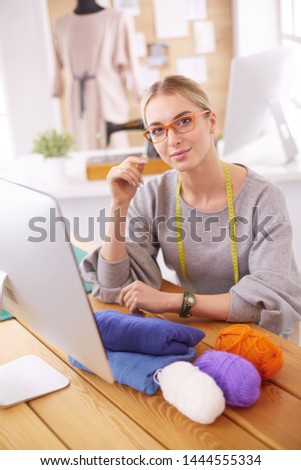 Fashion designer woman working in studio, sitting at thhe desk