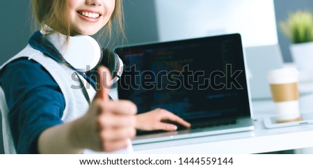 Young confident businesswoman working at office desk and typing with a laptop