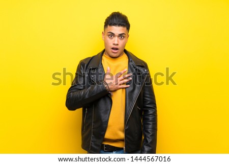 Young man over isolated yellow background surprised and shocked while looking right
