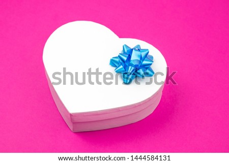 Heart shaped gift box with blue bow on a pink. Mock up. Empty place for an inscription. Present for the christmas, thanks giving day, birthday holiday. 