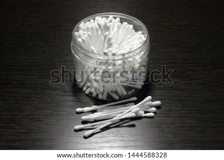 Cotton sticks in the package on a dark wooden background.
