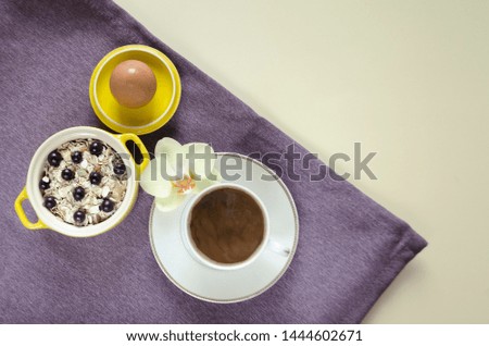 healthy eating concept. breakfast in bed. top view on a tray of oatmeal in a yellow pot, muesli with fresh blueberries, egg, coffee on a purple napkin on a pink background. copy space, soft focus