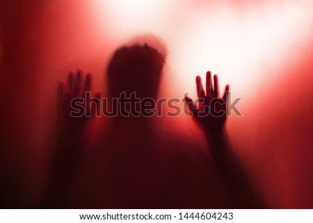 Shadow of the ghost hand behind frosted glass for horror concept