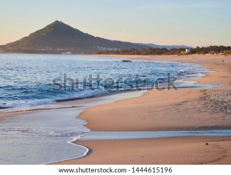 Woman in a white dress on the beach at Moledo, Portugal. With a mountain in background
