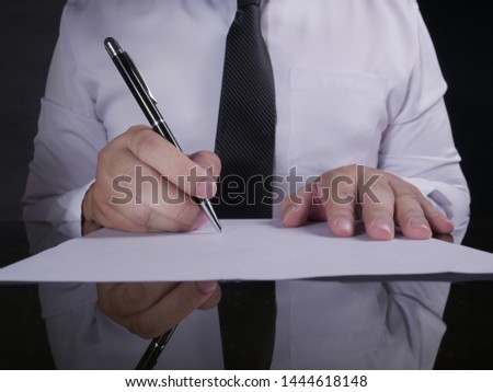 Close up image of businessman signing contract with black background