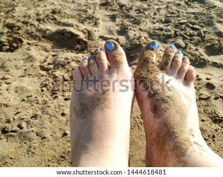 Close up picture of a woman feet covered with beautiful  sand on a beach 
