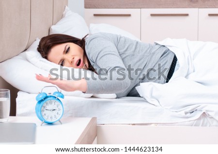Young woman lying on the bed in time management concept 