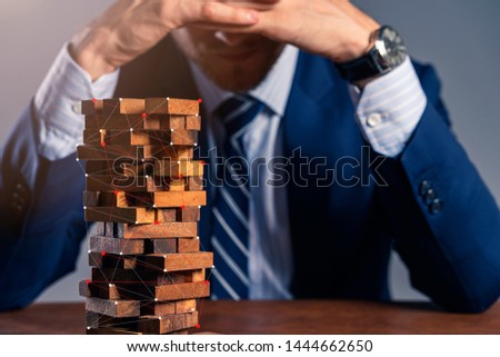 business man try to build wood block on wooden table and black background business organization startup concept
