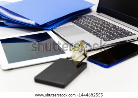 laptop computer on desk table in work office and external harddisk ,files folder ,mobile, glasses concept business life work office