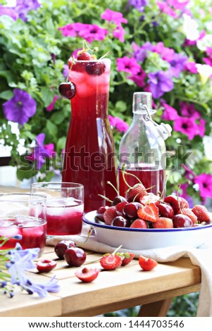 Summer berry cold drink. Iced drink from fresh seasonal berries on bright floral background.