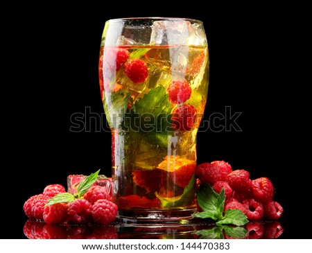 Iced tea with raspberries and mint on black background