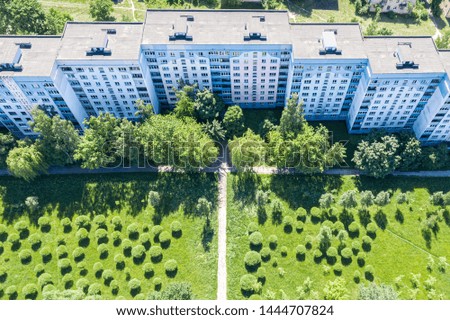 multistory residential buildings in suburban area with green lawn and trees. aerial shot in sunny summer day