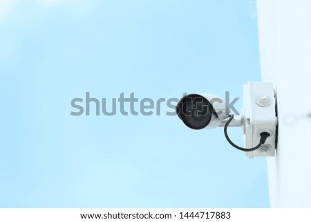 Modern CCTV security camera on building wall outdoors. Space for text