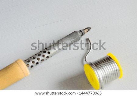 solder wire and soldering iron with wooden handle on gray background.