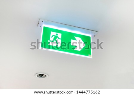 Fire exit sign. Emergency fire exit door exit door on ceiling. Green emergency exit sign showing the way to escape.