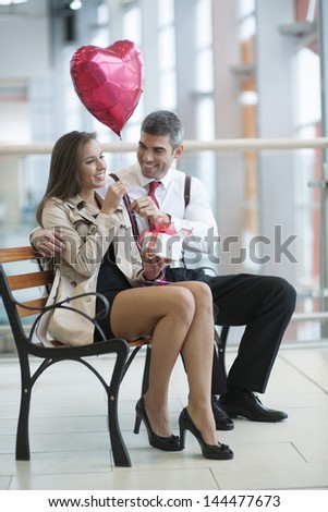 Man gives woman gift and heart shaped balloon