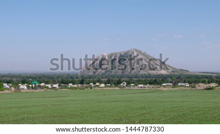 Oat field and village at the foot of Shihan Yuraktau. Republic of Bashkortostan. Russia. Royalty-Free Stock Photo #1444787330