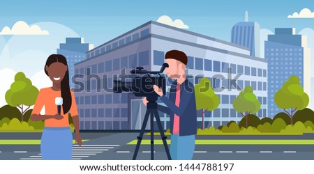reporter man with woman journalist presenting live news operator using video camera on tripod recording correspondent with microphone movie making concept cityscape background portrait horizontal
