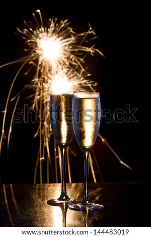 dark scene with two glasses of champagne and fireworks in the background