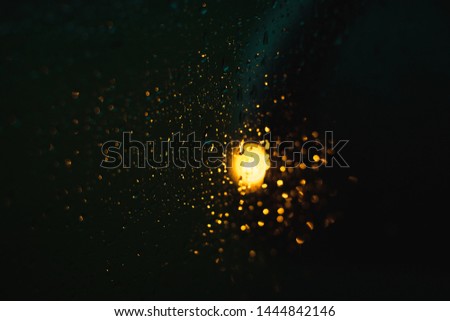 Light from the car indicator behind the glass and bokeh through the the droplets.