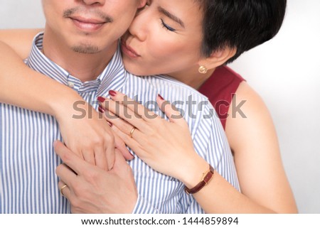 Closeup portrait of a couple: Middle aged smart looking asian woman (40-50) embracing and kissed her beloved husband. Lovers, Healthy marriage, Supportive, Medical care, Family life Insurance concept.